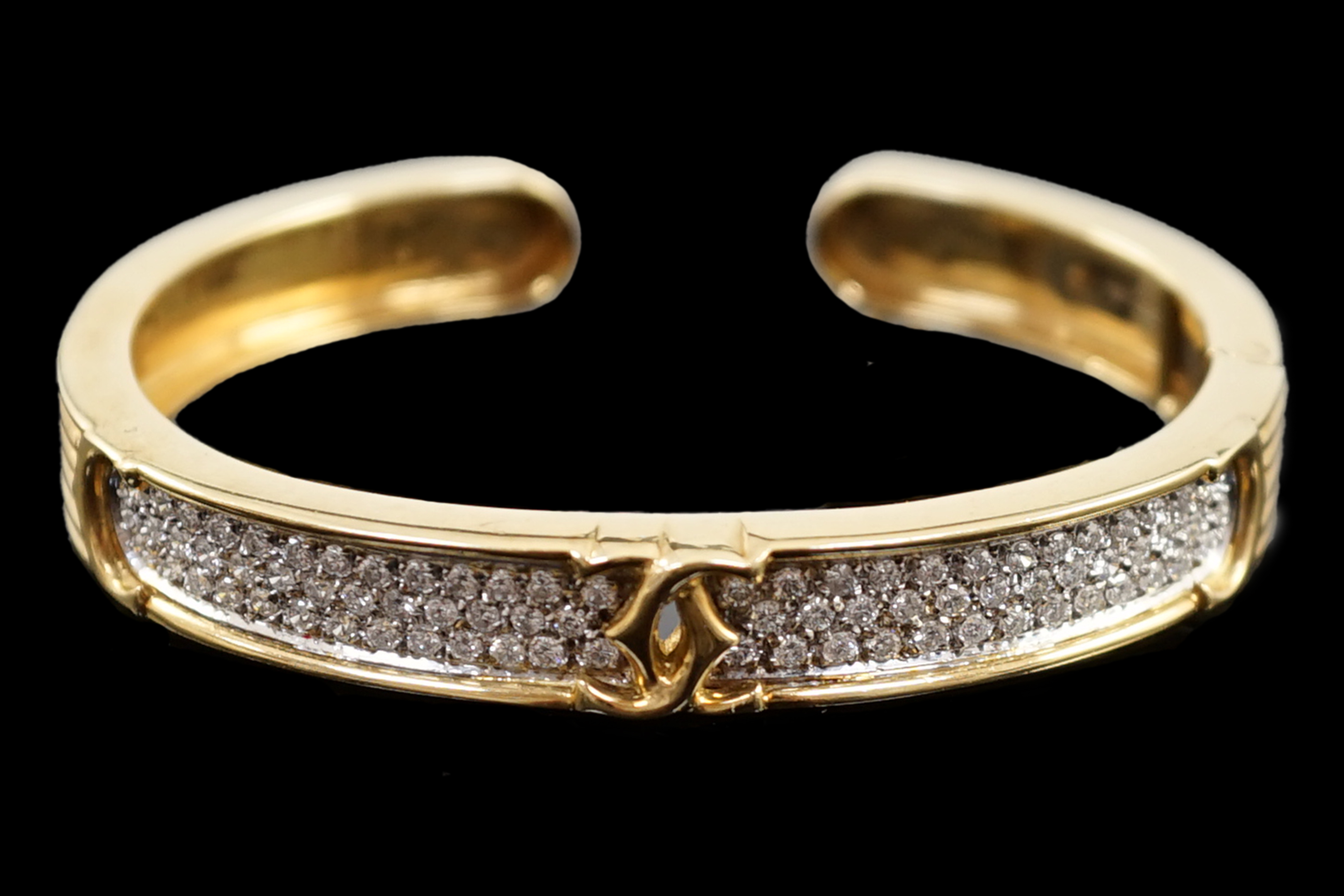 A modern 18k gold and pave set diamond Cartier open work hinged bangle